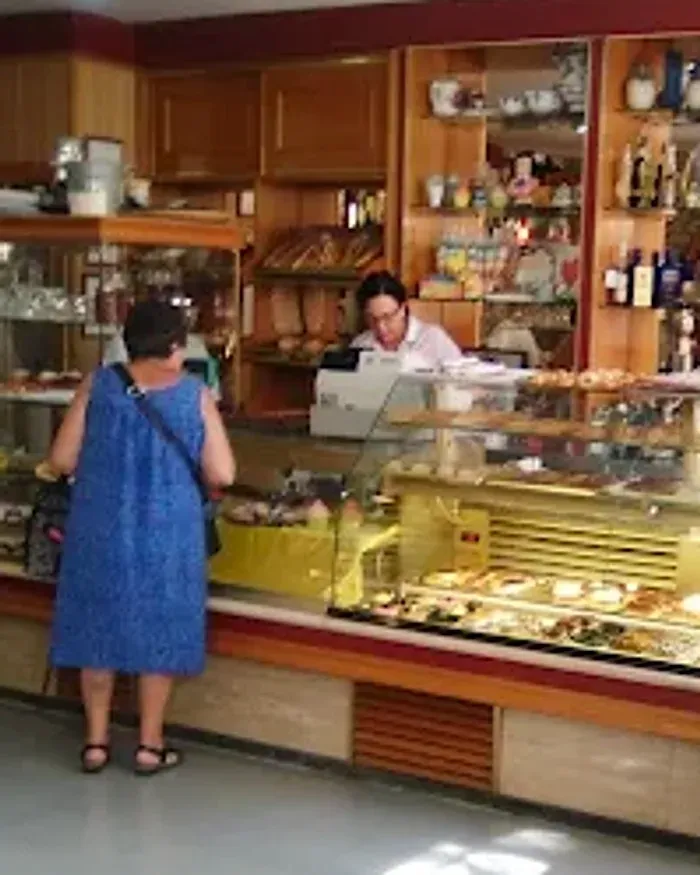 El mostrador de Bon Paladar por la mañana: la vitrina llena de pastelería y una clienta a la que están atendiendo.