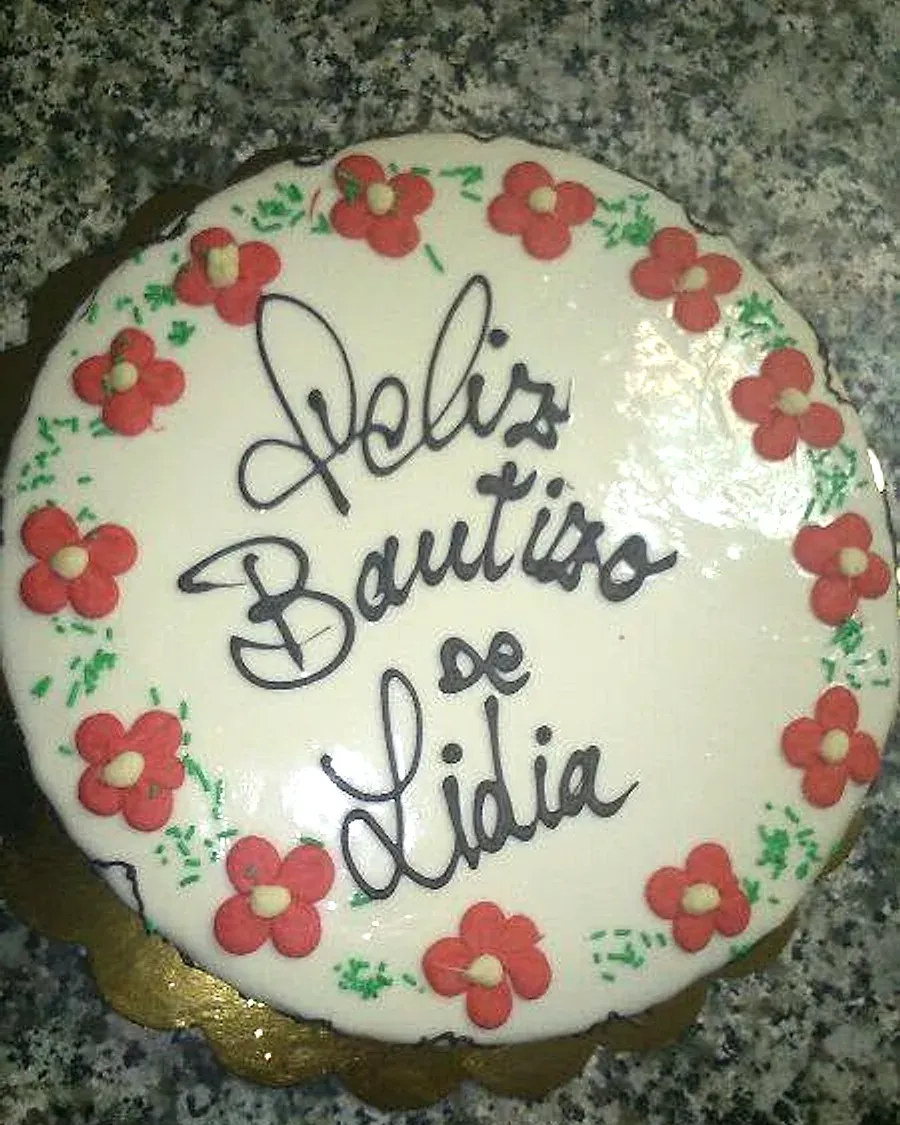 Tarta de bautizo de Bon Paladar, con el nombre escrito a mano y un borde de flores hechas con manga pastelera.